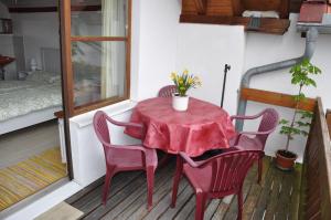 a red table and chairs on a balcony with a bed at Ferienwohnung F. Keller in Kressbronn am Bodensee +4 photos