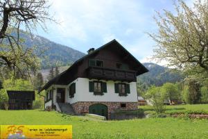 una pequeña casa en un campo con montañas en el fondo en Haus Seeruhe - direkt am Grundlsee, en Grundlsee
