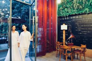 two women in white standing outside a glass door at Ancient Street No.5 Youth Chic Hotel in Wuyishan