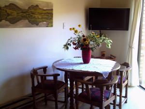 a dining room table with a vase of flowers on it at Kozmos in Clarens +3 photos