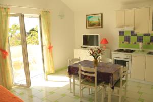 una cucina con tavolo e sedie e una cucina con porta aperta di Apartments Nejašmić - little house for peaceful and domestic vacation a Bol