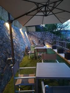 un patio con mesas, sillas y una sombrilla en B&B Via delle 5 Terre, en La Spezia