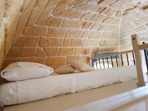 een bed met kussens voor een bakstenen muur bij Dimora La Nicchia in Polignano a Mare