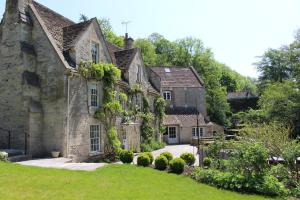 una antigua casa de piedra con un patio verde en Midford Mill, en Bath