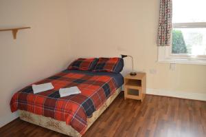a bedroom with a bed with a plaid blanket and a window at Library View Villa Holiday Home in Dublin