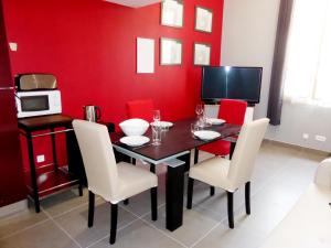 ein Esszimmer mit roten Wänden sowie einem Tisch und Stühlen in der Unterkunft Les Logis des Vignobles Sainte Emilion en Duplex n 1 avec terrasse in Saint-Émilion