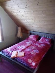 Una cama con sábanas rosas y dos libros. en Holiday home en Ogre