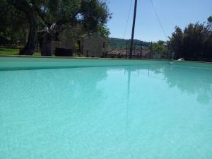 una gran piscina de agua azul frente a una casa en Casa in campagna per vacanze in Umbria con piscina, en Vicolo Rancolfo