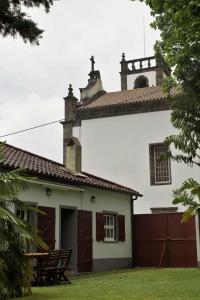 a white house with a roof and a gate at Casa da Igreja Velha in Furnas