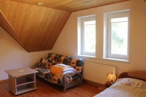 ein Schlafzimmer mit einem Bett und einem Sofa sowie zwei Fenstern in der Unterkunft Paliepgiris in Palanga