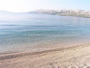 a beach with blue water and mountains in the background at Apartments Loncar-near Zrće beach in Novalja