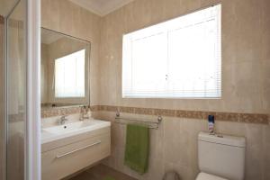 Un baño con lavabo, inodoro y espejo. en Somerset West Vacation Rental - Experience the Best of Cape Town - Wine, Golf, Sea, en Somerset West