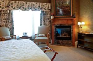 a bedroom with a fireplace and a bed and a chair at Cliff House at Pikes Peak in Manitou Springs