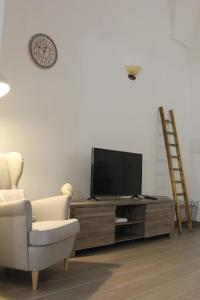 salon z telewizorem, krzesłem i zegarem w obiekcie Dimora della Castellana w mieście Lecce