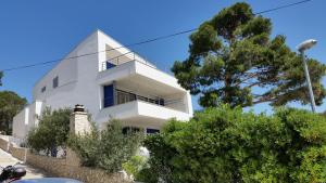 ein weißes Haus an einer Steinmauer mit Bäumen in der Unterkunft Villa Big Blue, Tisno in Tisno