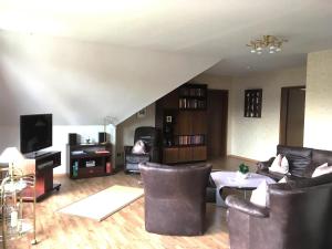ein Wohnzimmer mit einem Sofa, Stühlen und einem TV in der Unterkunft Ferienwohnung Will in Walkenried