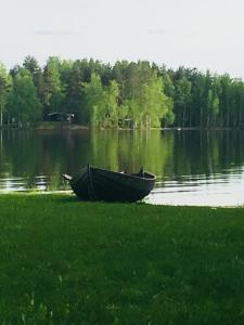 un barco sentado en la orilla de un lago en Lomatila Ollila Farm Stay en Kerimäki