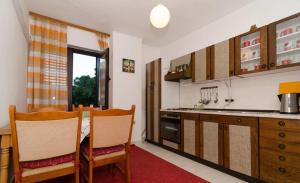 a kitchen with wooden cabinets and a table and chairs at Apartments Anica in Sobra