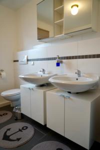 a bathroom with two sinks and a toilet at M&A Ferienwohnungen Oberbayern in Peiting