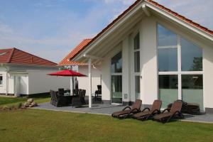 a patio with chairs and an umbrella in front of a house at Villa Ankerplatz in Trent