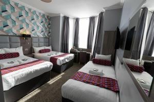 um quarto de hotel com três camas e janelas em Euro Hotel em Londres