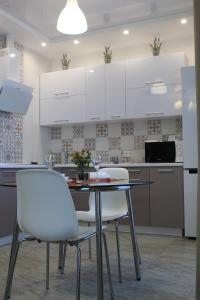 a kitchen with a table and two white chairs at Apartment Deluxe on Krasnopresnenskaya in Volgograd