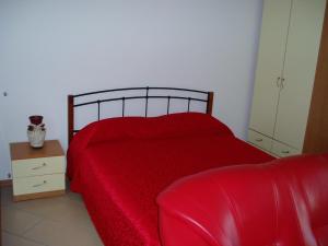 a bedroom with a red bed and a chair at Apartment studio TA-TI in Umag