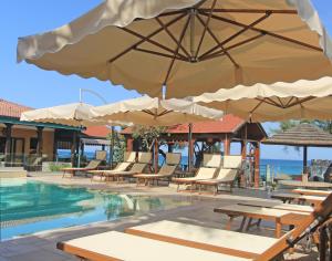 a pool with tables and chairs and umbrellas at Villaggio Tramonto in Capo Vaticano