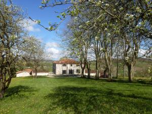 a house in a field with trees in the foreground at Domaine de calbiac in Dolmayrac