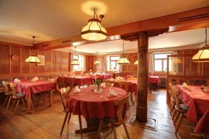 une salle à manger avec des tables rouges, des chaises et des lumières dans l'établissement Gasthaus zum Hirschen, à Oberrimsingen