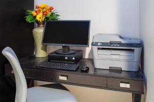 a desk with a computer and a printer and a vase with flowers at Baymont by Wyndham Phoenix I-10 near 51st Ave in Phoenix