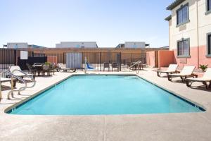 a swimming pool with chairs and tables on a building at Baymont by Wyndham Phoenix I-10 near 51st Ave in Phoenix
