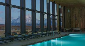 a hotel with a pool with chairs and a mountain at Río Serrano Hotel + Spa in Torres del Paine