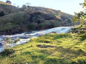 a river on a grassy hill next to a field at Hospedagem Roze - in São José de Pedra Menina
