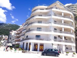 a white building with a car parked in front of it at Beach Apartment in Rafailovici