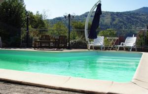 a swimming pool with an umbrella and chairs at Au pied du Markstein in Oderen