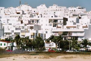 a white building with cars parked in front of it at Apartamento San Isidro in Conil de la Frontera