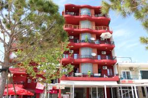 un edificio rojo con árboles delante de él en Hotel Veizi, en Himare