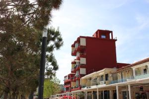 um edifício vermelho com uma torre em cima dele em Hotel Veizi em Himare