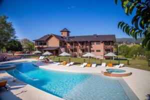 a large house with a swimming pool in front of a house at Ayres del Champaqui Hotel Boutique Experiencial & Spa in Villa General Belgrano