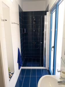 a bathroom with a shower with blue tiles at Island Apartment in Kavála