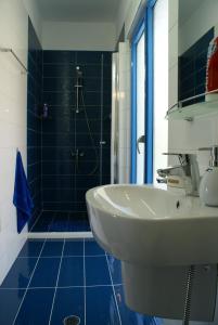 La salle de bains est pourvue d'un lavabo et d'une douche avec du carrelage bleu. dans l'établissement Island Apartment, à Kavala