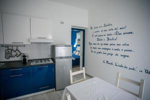 a kitchen with blue cabinets and writing on the wall at La casa del pescatore in Oliveri