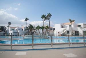 a large swimming pool with palm trees and buildings at Canary Islands getaway in Caleta De Fuste +26 photos