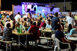 a crowd of people sitting at tables in front of a stage at Apartment Sea in Galižana