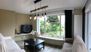 a living room with a couch and a large window at Maison du golf in Nieuwpoort