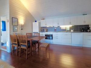 a kitchen with white cabinets and a wooden table and chairs at Eagle View Lofoten in Bøstad