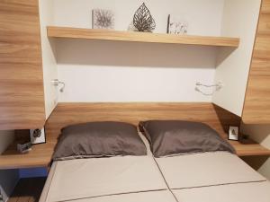 a bed in a room with wooden shelves at Mobile Home Seahorse Camp Soline in Biograd na Moru