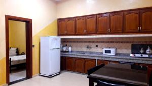 a kitchen with wooden cabinets and a white refrigerator at Joudia in Temara