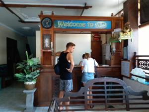 two people standing at a counter in a restaurant at Kembar Inn Padangbai in Padangbai